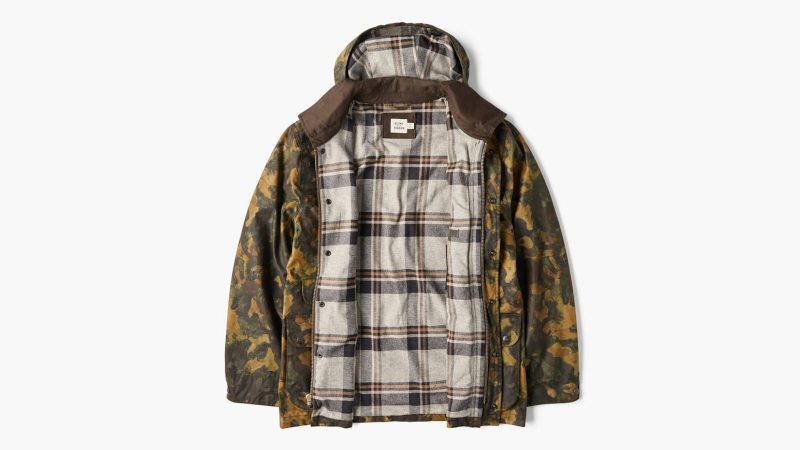 Flint and Tinder’s Flannel-Lined Waxed Hudson Jacket in limited-edition kelp camo featuring Halley Stevensons waxed cotton canvas, flannel lining, removable hood, moleskin trim, and multiple utility pockets.