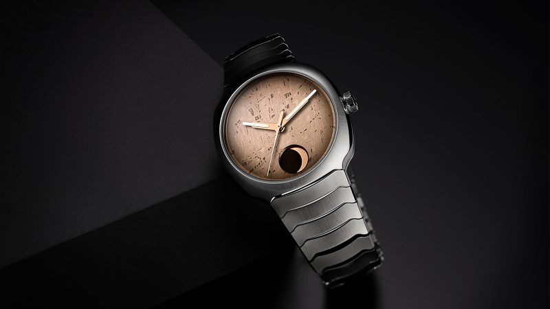 The H. Moser & Cie. Streamliner Perpetual Moon Concept Meteorite watch with a golden Gibeon meteorite dial, steel integrated bracelet, and moon phase at 6 o'clock.