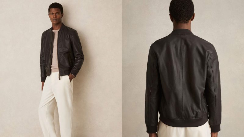 The REISS Cast leather bomber jacket features grained leather, gold-tone hardware, ribbed trims, and a modern minimalist silhouette.