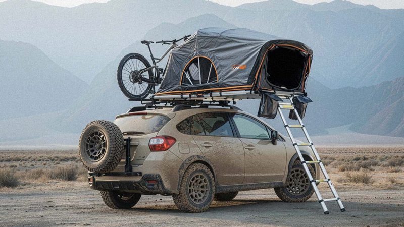 The Roofnest Meadowlark ultralight rooftop tent is mounted on a compact SUV, featuring an open fold-out design with an integrated ladder and foam mattress.