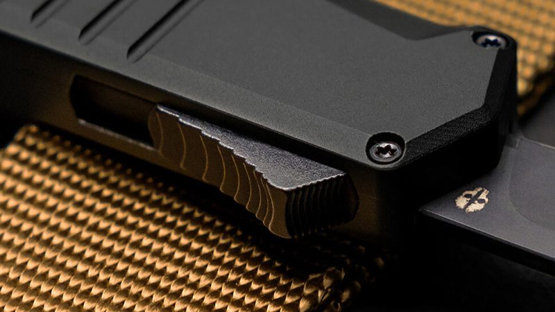 The TEKTO A2 Badger tactical folding knife with a black titanium-coated D2 steel blade and a lightweight carbon fiber handle.