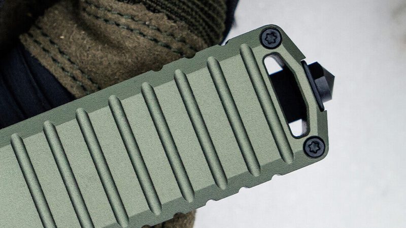 The TEKTO A2 Badger tactical folding knife with a black titanium-coated D2 steel blade and a lightweight carbon fiber handle.