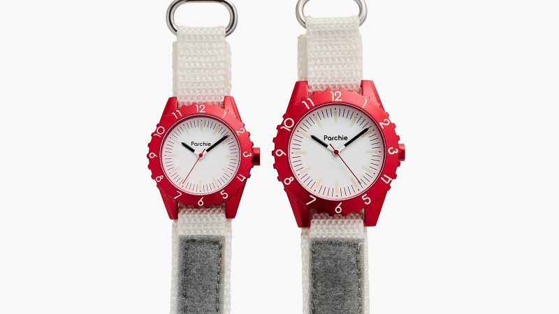 The Parchie Lunar-Time Limited Edition for Hodinkee is a space-inspired watch with a red aluminum case, a white dial, a Velcro strap, and available in 32mm and 36mm sizes.