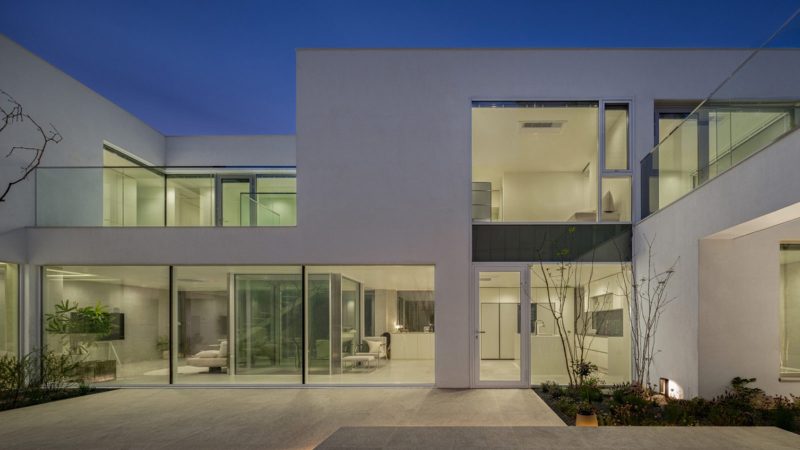 Modern minimalist VEGA House by Archirie featuring white perimeter walls, integrated courtyard gardens, and a sleek second-story terrace with lush plantings.