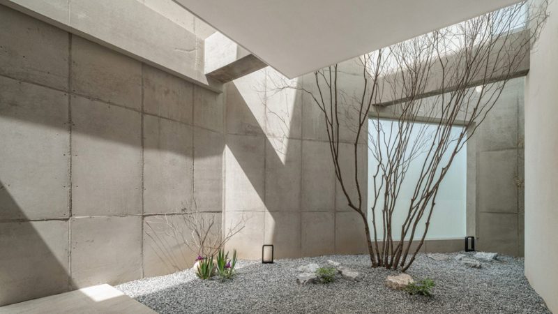 Modern minimalist VEGA House by Archirie featuring white perimeter walls, integrated courtyard gardens, and a sleek second-story terrace with lush plantings.