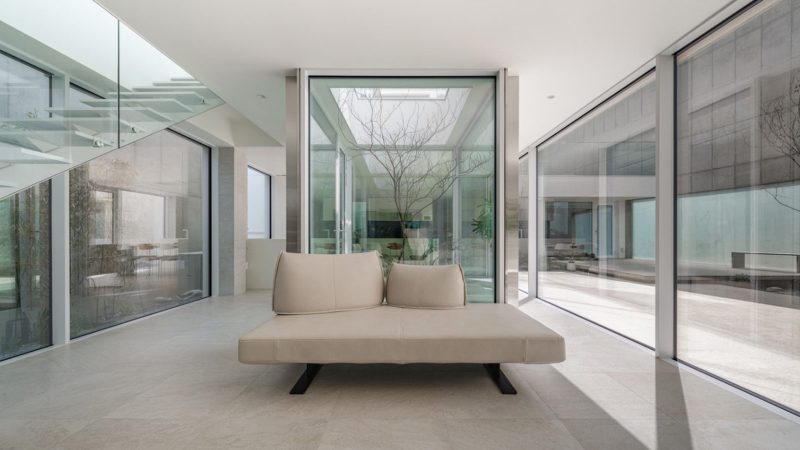 Modern minimalist VEGA House by Archirie featuring white perimeter walls, integrated courtyard gardens, and a sleek second-story terrace with lush plantings.