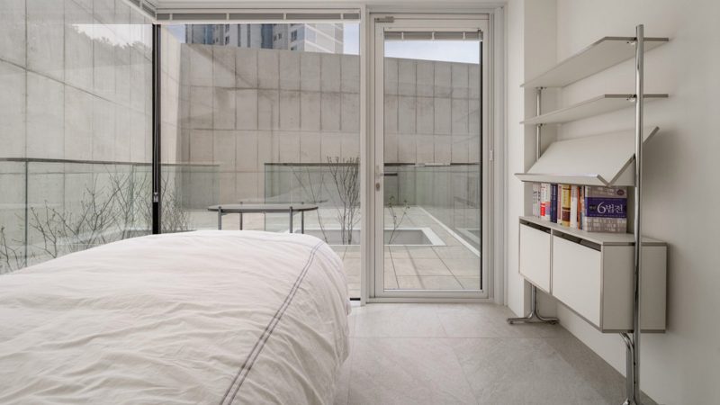 Modern minimalist VEGA House by Archirie featuring white perimeter walls, integrated courtyard gardens, and a sleek second-story terrace with lush plantings.