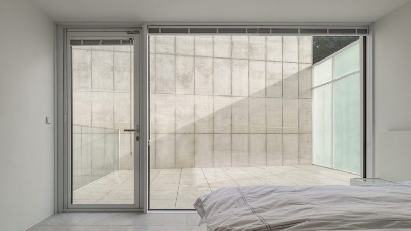 Modern minimalist VEGA House by Archirie featuring white perimeter walls, integrated courtyard gardens, and a sleek second-story terrace with lush plantings.